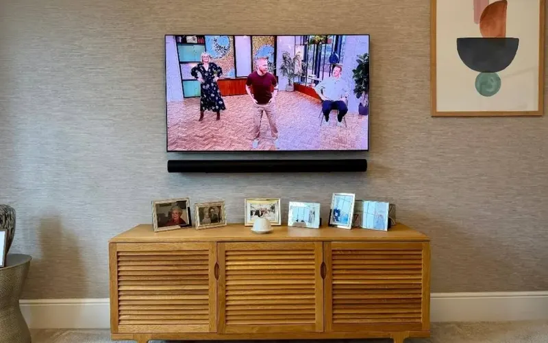 Wall-mounted TV and soundbar above an oak cabinet